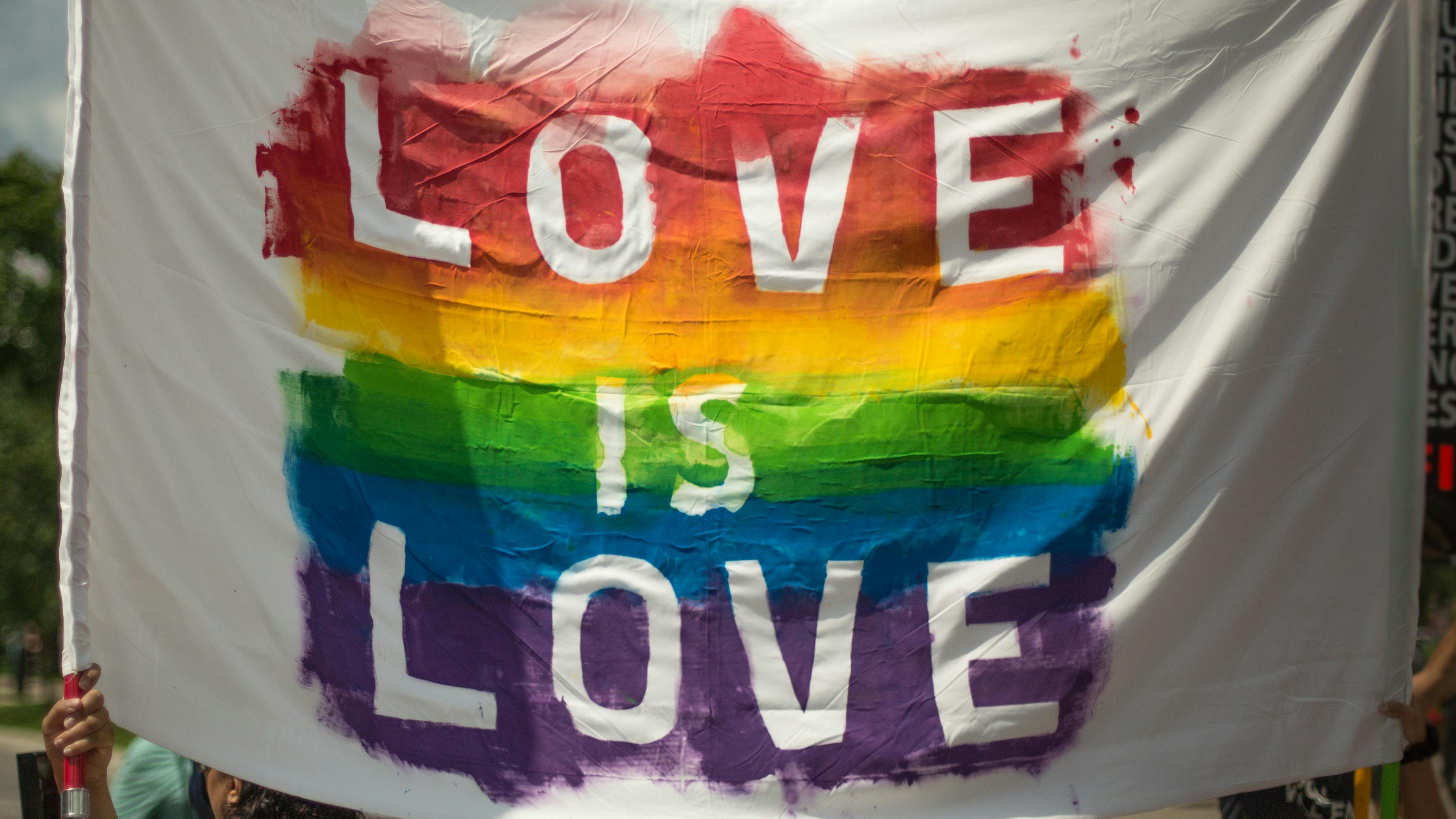 Colorful 'Love is Love' pride banner at a parade in London, Ontario celebrating equality and diversity.