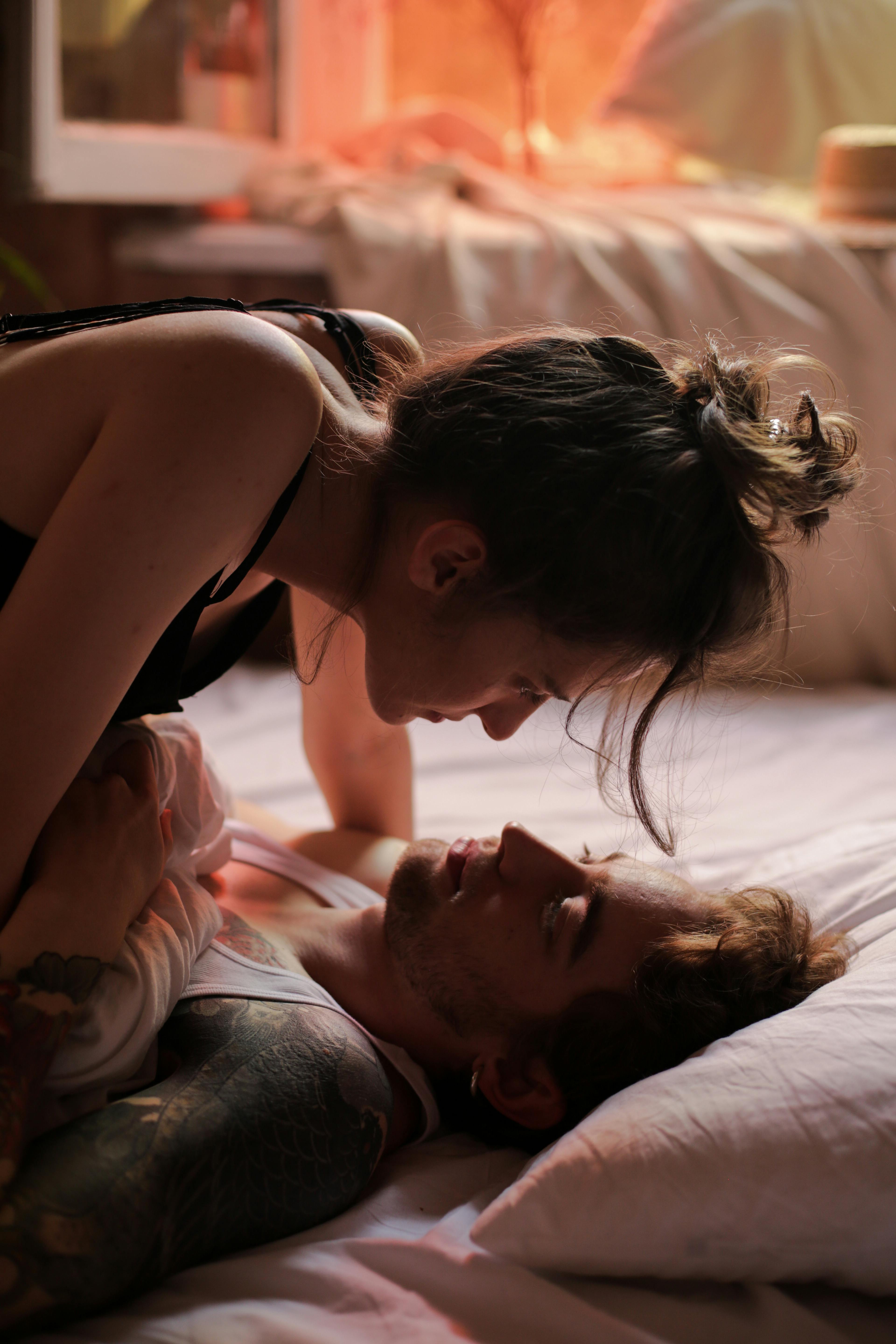 Couple sharing intimate moments in a softly lit, cozy bedroom.