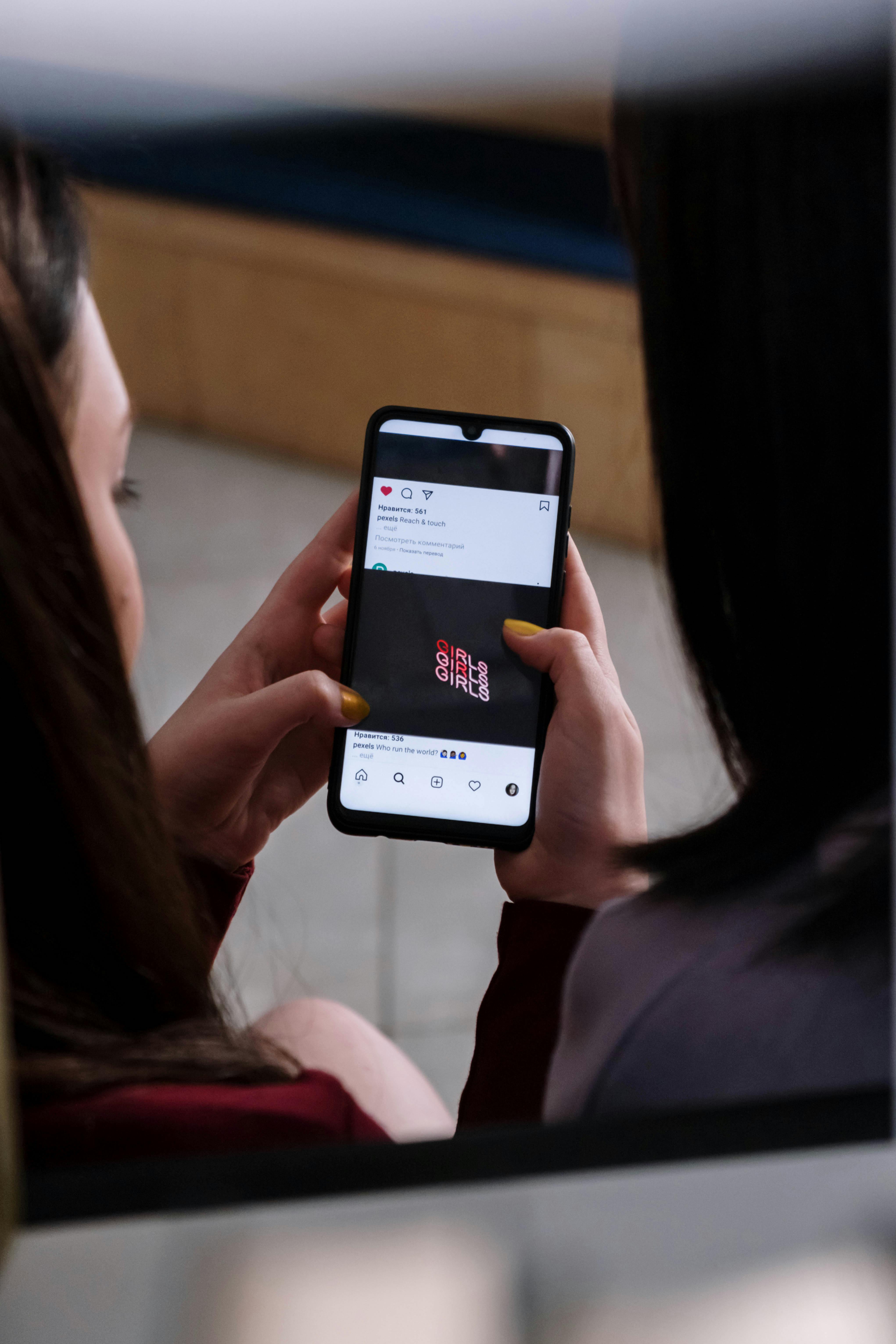 A woman holding a smartphone engages with social media content, depicted in a close-up view.