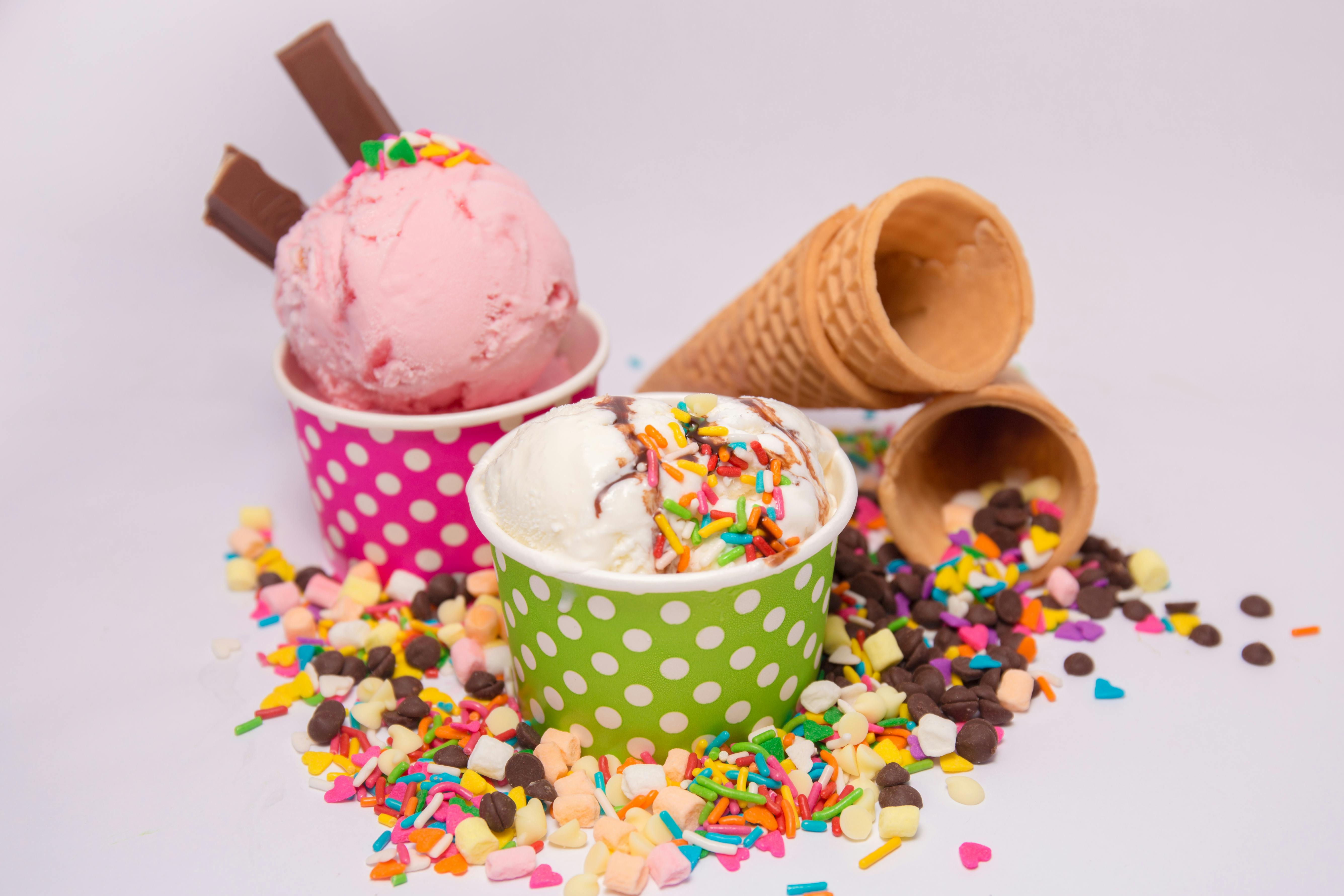 Delicious ice cream in vibrant cups with scattered sprinkles and waffle cones.