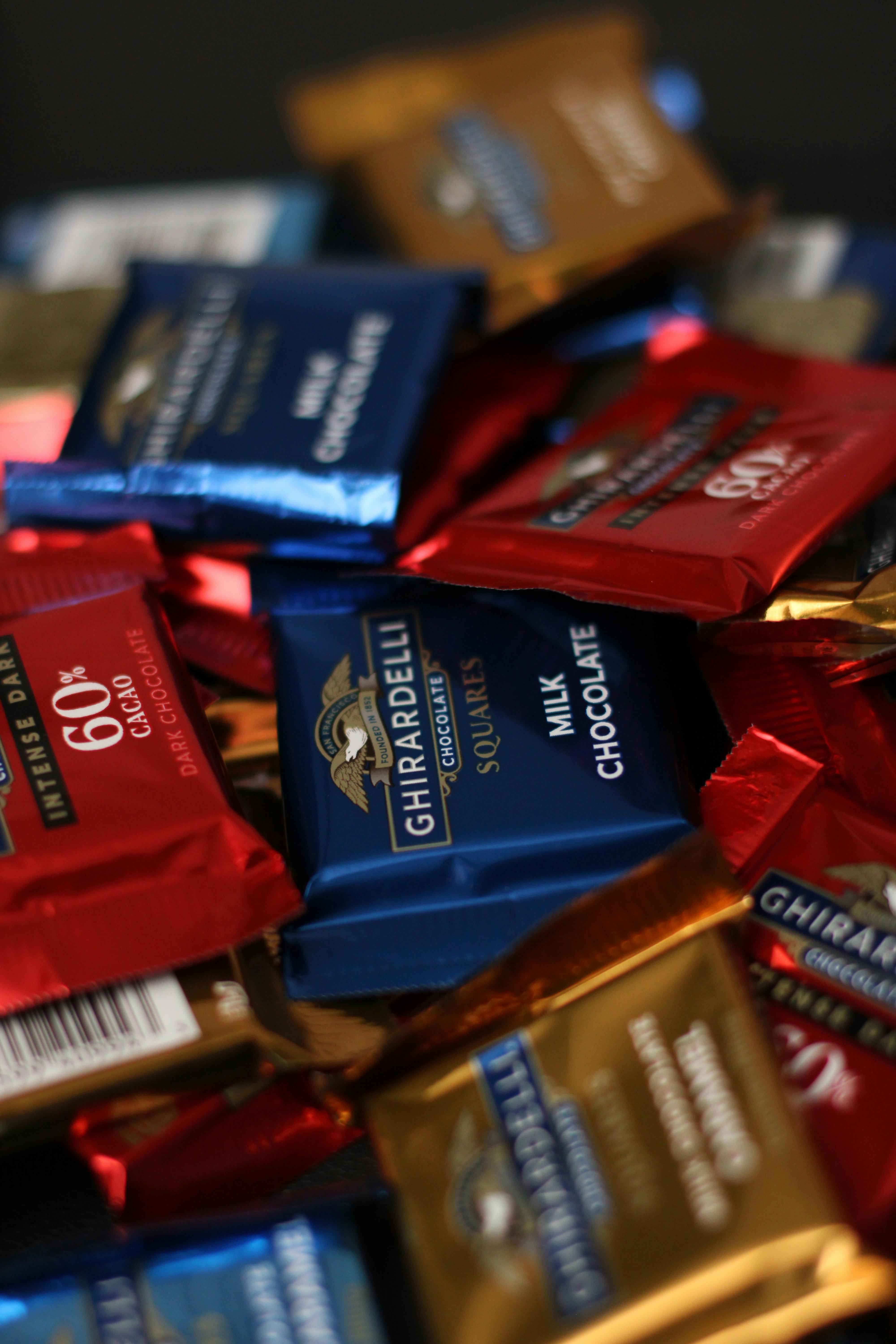 Close-up of a variety of Ghirardelli chocolate squares in colorful wrappers.