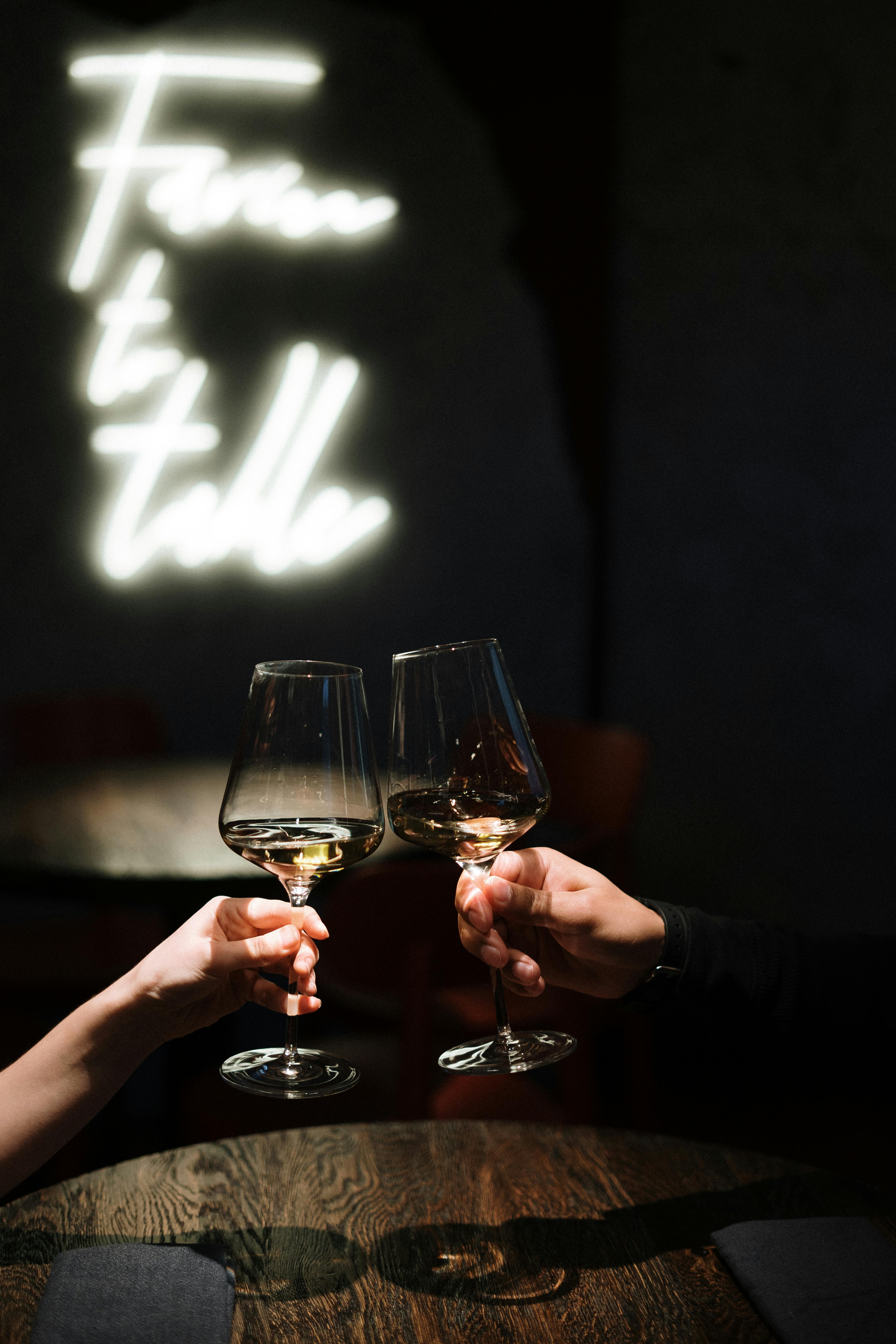 Two people clinking wine glasses in a warmly lit restaurant, creating a romantic ambiance.