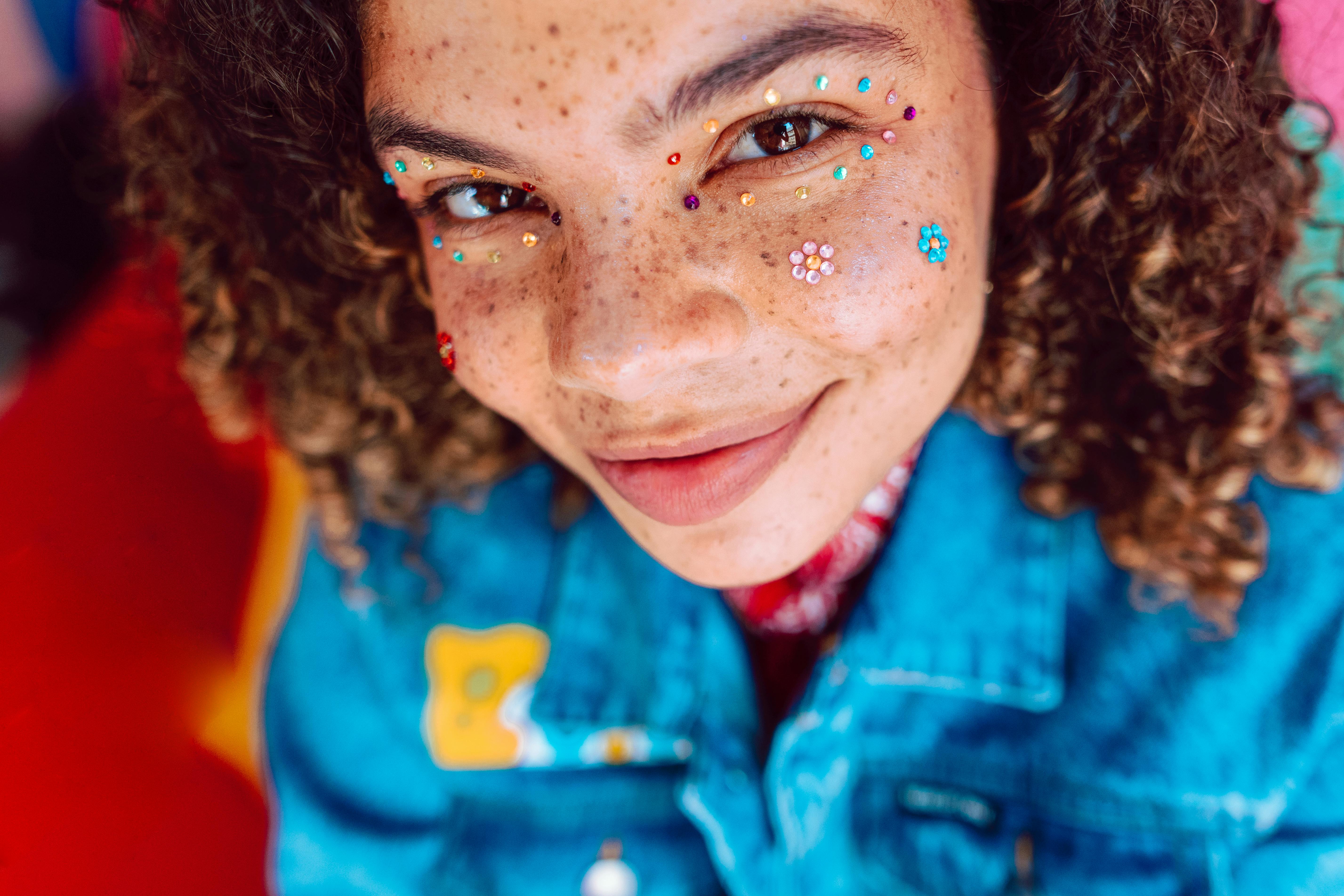 Vibrant portrait featuring a young person with creative face makeup, exuding youthful joy and style.