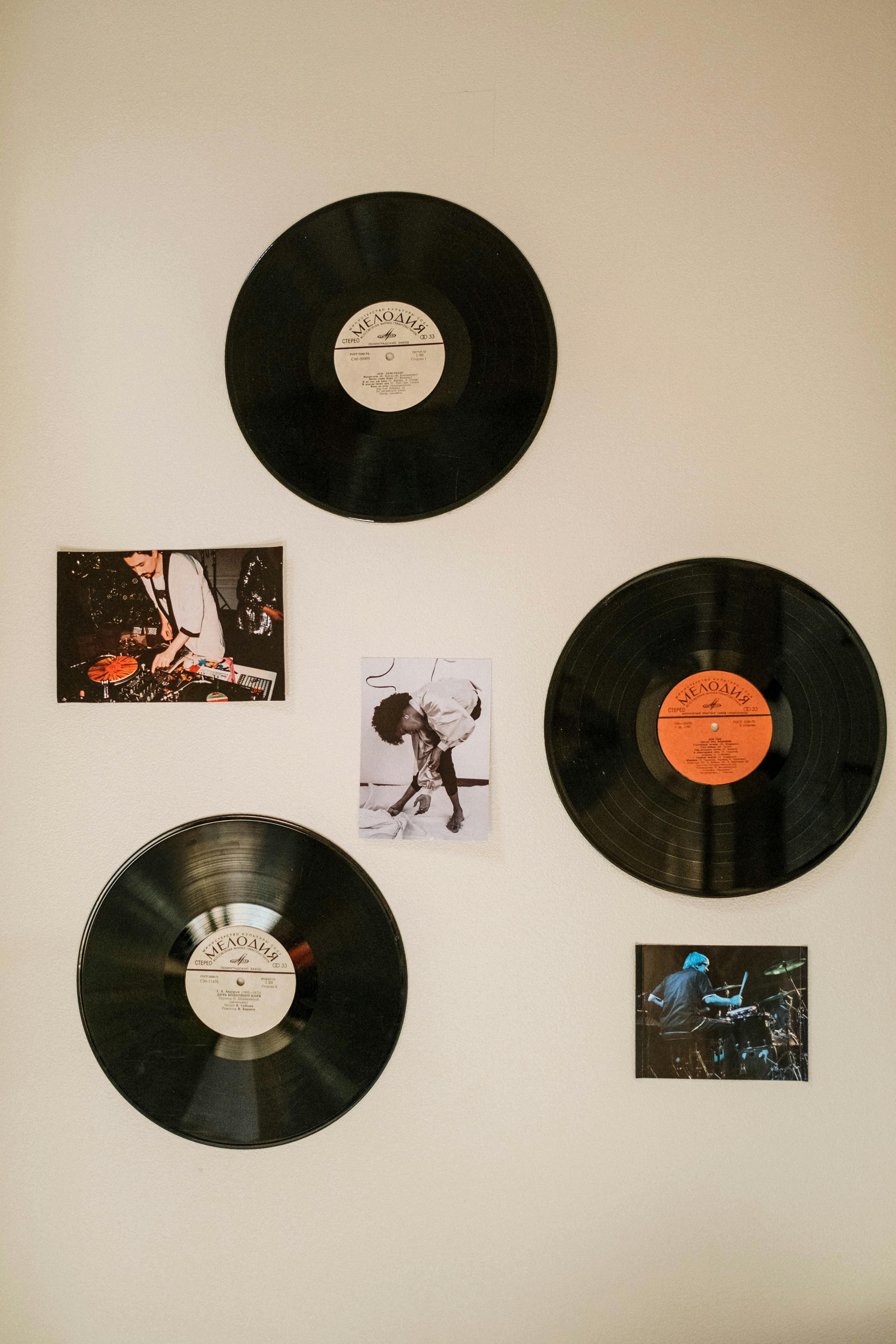 A collection of vinyl records and music photos displayed on a white wall.