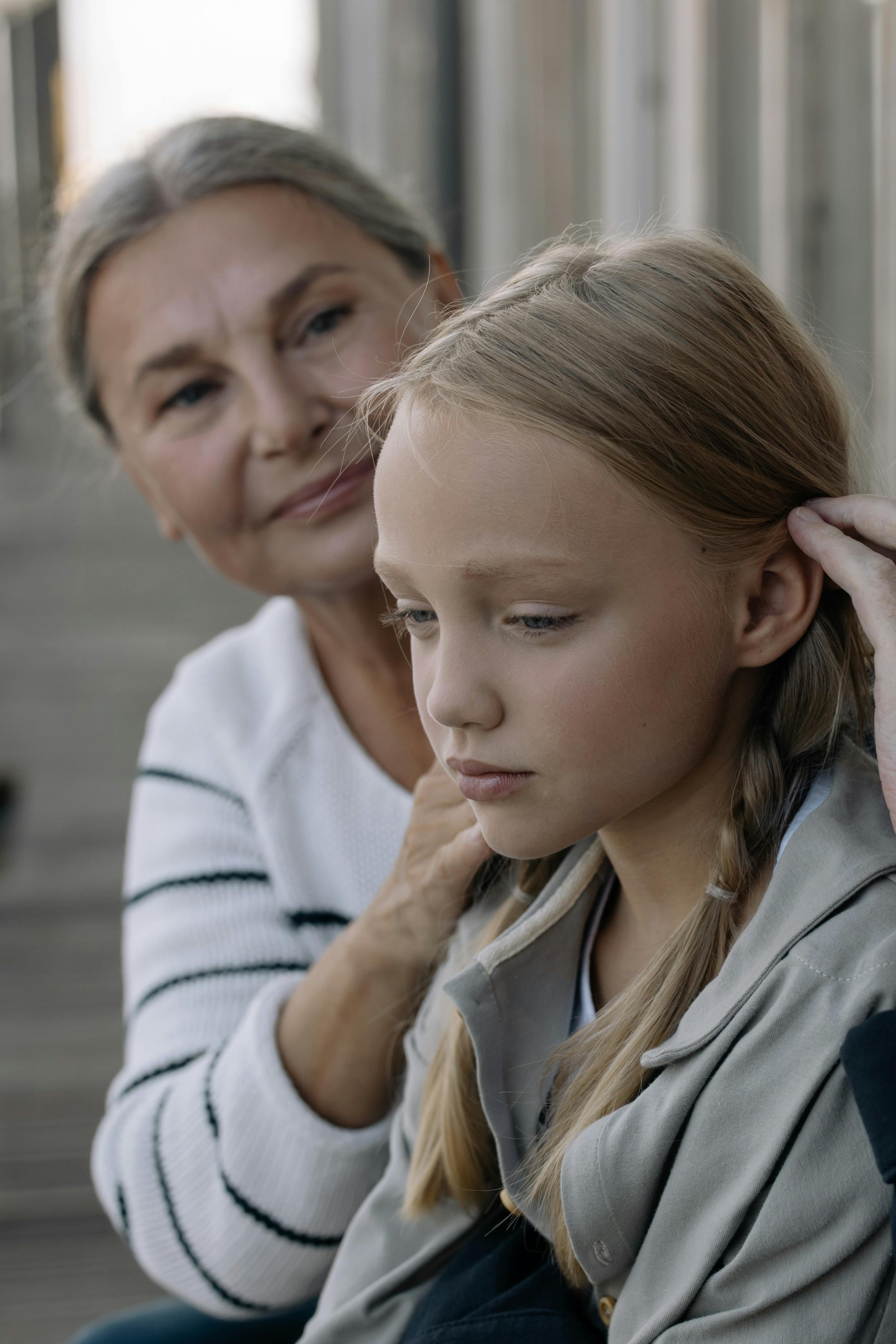 A thoughtful grandmother comforting her granddaughter outdoors, capturing the bond between generations.