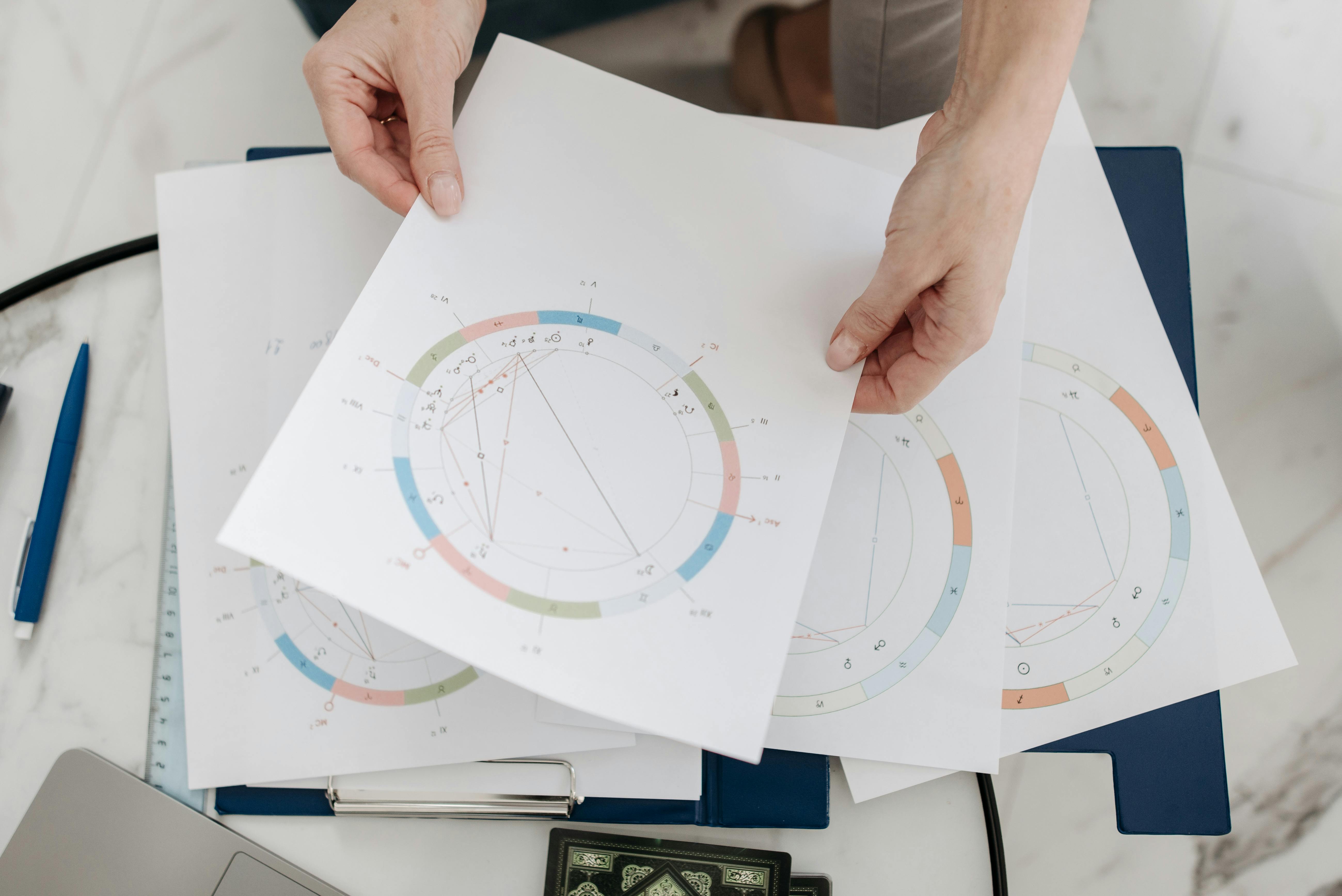 Hands holding astrological charts and graphs, symbolizing horoscopes and fortune-telling.